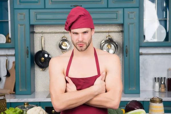 Macho chef in red hat, apron on bare torso — Stock Photo, Image
