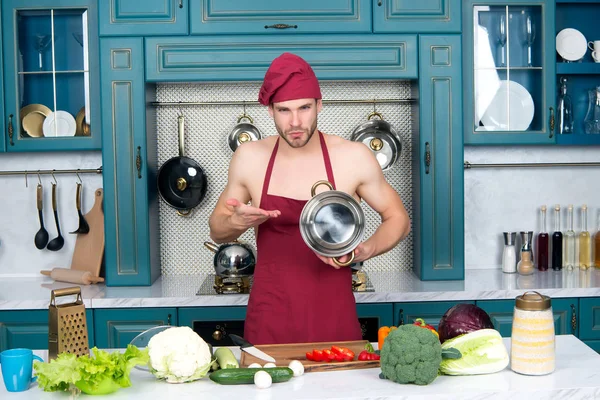 Man chef-kok in schort op kale romp wijzen op steelpan — Stockfoto
