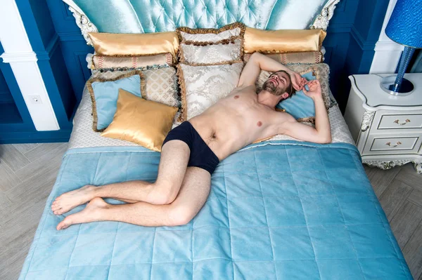 男は青いベッドで寝る — ストック写真