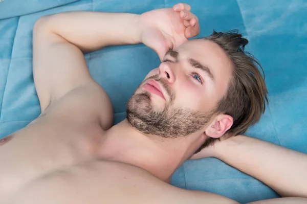 男子气概躺在蓝床封面 — 图库照片