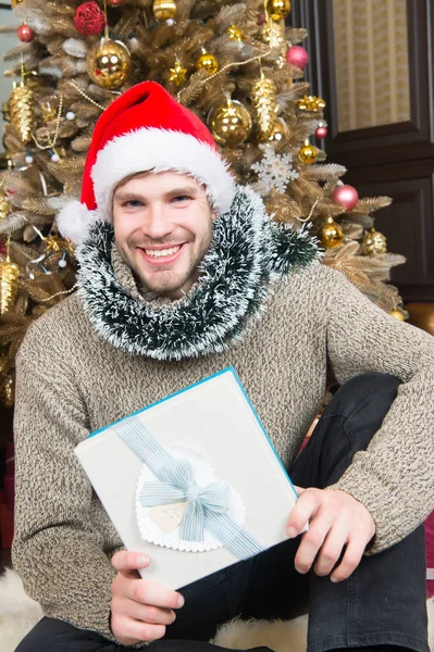 Τύπος χαμόγελο σε το καπέλο santa με παρόν στο χριστουγεννιάτικο δέντρο. — Φωτογραφία Αρχείου
