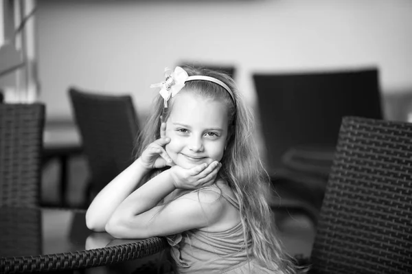 Pequena menina sorridente em vestido azul perto da mesa do café — Fotografia de Stock