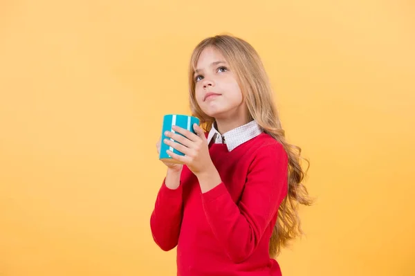 Niño con la cara pensante mantenga taza azul sobre fondo naranja — Foto de Stock