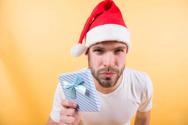 Mann mit Weihnachtsmütze mit Geschenk auf orangefarbenem Hintergrund — Stockfoto