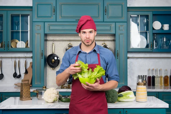 De chef van de man in rode hoed, schort greep groene salade verlaat — Stockfoto