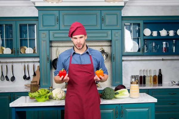 Macho em chapéu de chef, avental com pimenta vermelha e laranja — Fotografia de Stock