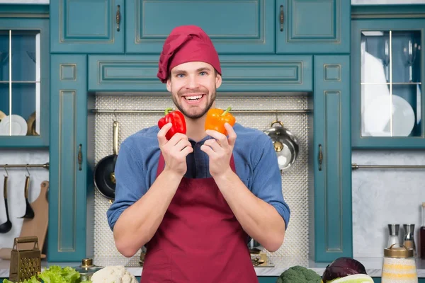 Homem de chapéu de chef sorriso com pimenta vermelha e laranja — Fotografia de Stock