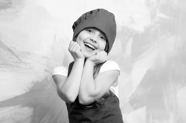 Pequeña chica chef con cara feliz en sombrero y delantal — Foto de Stock