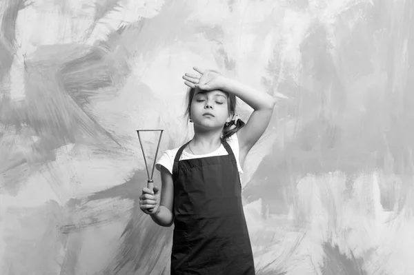 Malý unavený dívka kuchař v hospodářství cook zástěra vaření tool — Stock fotografie