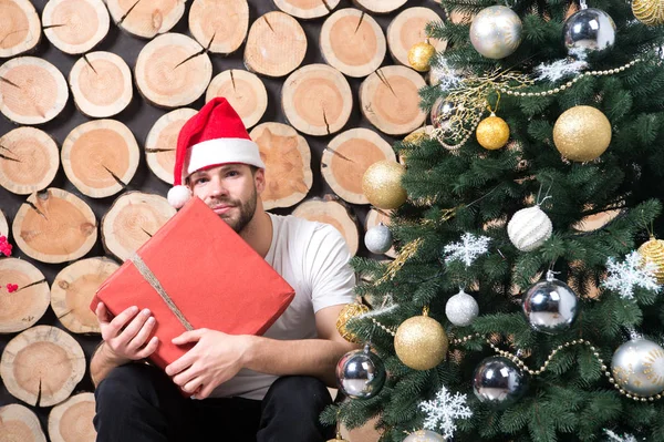 Macho i röd hatt hålla gåva på ved — Stockfoto