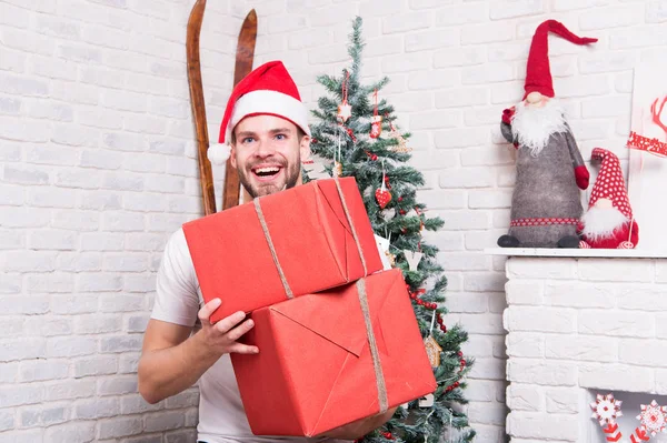 Kerst macho in rode hoed glimlach met ingepakte cadeautjes — Stockfoto