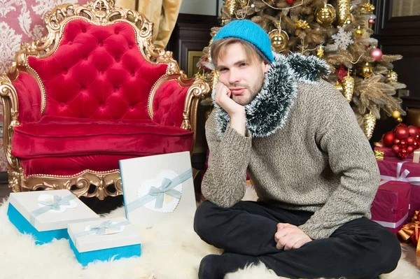 Hombre con cara infeliz sentarse en el árbol de Navidad — Foto de Stock