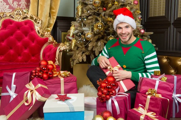 Hombre en sombrero de santa con regalos en el árbol de Navidad — Foto de Stock