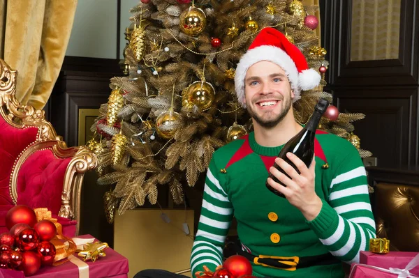 Guy in santa hat glimlach met champagnefles — Stockfoto