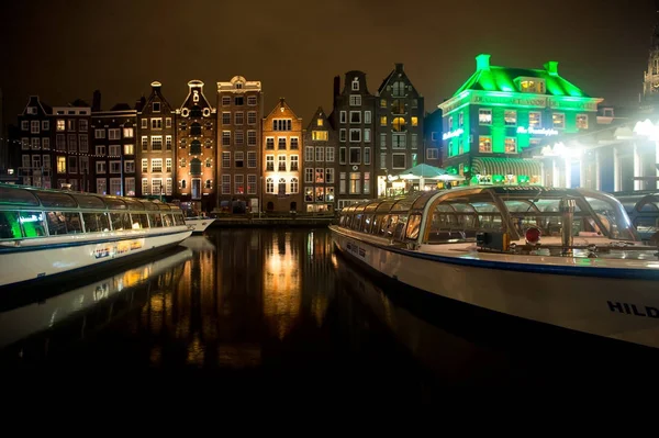 Туристические лодки на речном канале и исторические здания в Амстердаме — стоковое фото