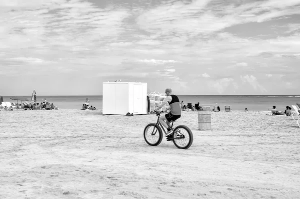 Людина велосипед їзда на піщаному пляжі вздовж узбережжя синє море — стокове фото