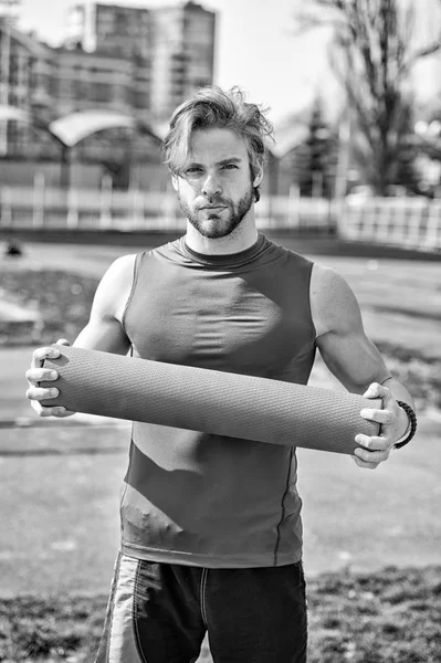 Hombre muscular sosteniendo yoga o colchoneta de fitness para hacer ejercicio — Foto de Stock