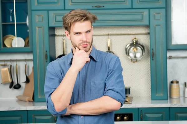Man with thinking face touch bearded chin in blue shirt