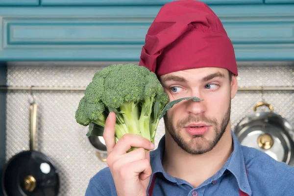 Cara de chapéu de chef vermelho olhar para brócolis verde — Fotografia de Stock
