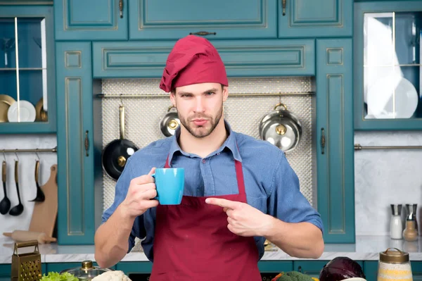Kerl zeigt mit Finger auf blaue Tasse in Küche — Stockfoto