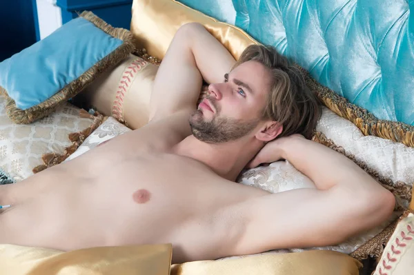 A szakállas és szexi törzsű fickó az ágyon fekszik. — Stock Fotó