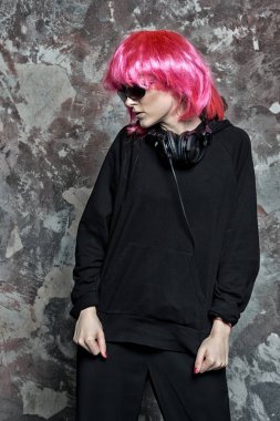 Güneş gözlüklü kız, soyut duvarda kulaklık, klasik filtre.