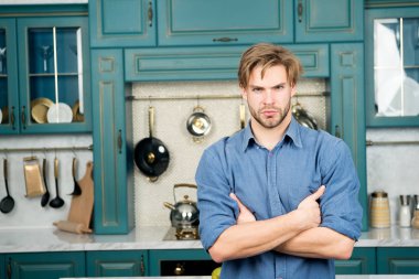 Maço ciddi bir yüz ile stand katlanmış ellerle mutfakta