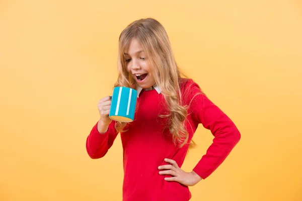 Enfant avec visage surpris tenir tasse bleue sur fond orange — Photo