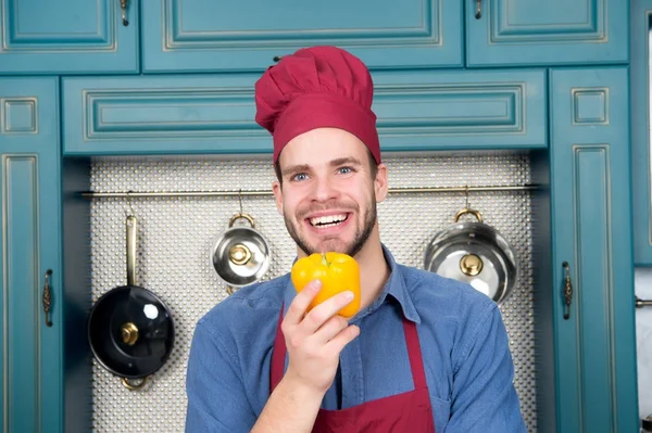 Cara em chapéu de chef sorriso com pimenta amarela na cozinha — Fotografia de Stock