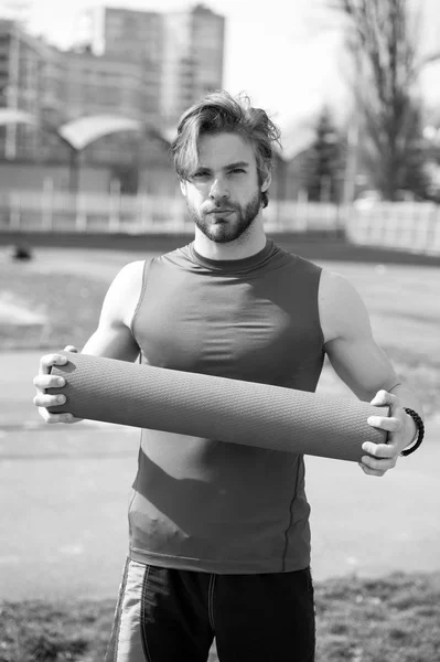 Muscular man holding yoga or fitness mat for exercise — Stock Photo, Image