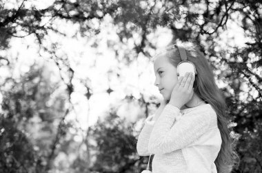 Güzel küçük kız yaz günü kulaklıkla müzik dinliyor ve eğleniyor.