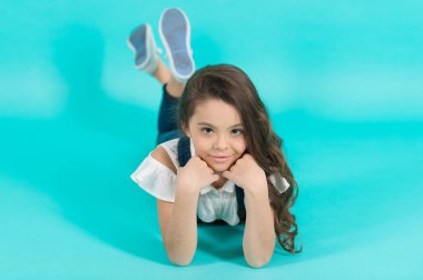 Mavi arka plan katta küçük kız. Moda giysiler içinde uzun esmer saçlı çocuk. Moda, güzellik, bak. Çocukluk, varoluş, gençlik, punchy pastel