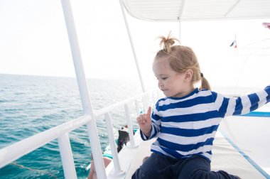 Yaz tatil kavramı. Yatta güneşli sarı saçlı çocuk. Çocuk denizci gömlekli mavi denizlerde yelken. Macera, keşif, Yolculuk tutkusu. Seyahat hedef, seyahat eden yolcu,.