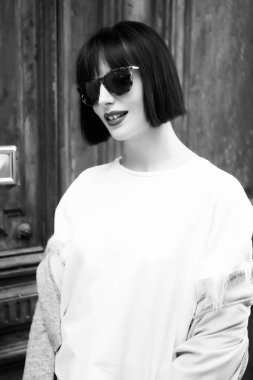 Moda model poz ahşap arka plan üzerinde. Şık kısa esmer saçlı kadın. Güzellik ve vintage moda. Moda gözlük ve gömlek gülümseyen kız. Göz ve retro tarzı, siyah ve beyaz