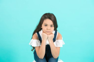 Mavi arka planda çocuk çene desteği. Uzun esmer saçlı, kotlu bir kız. Güzellik, moda, bak, konsept, kopyalama alanı