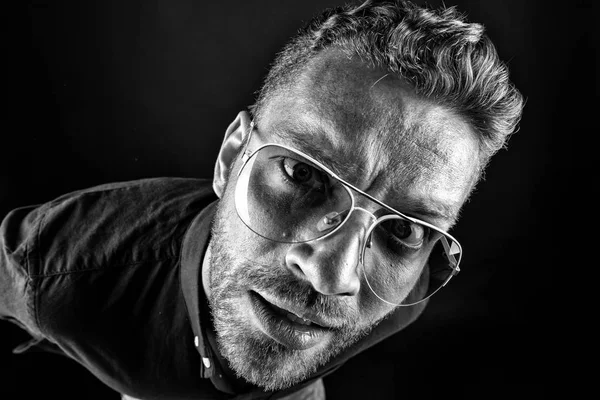 Bachelor in glasses look with curious face on dark background. Fashion, style, accessory. Beauty, barber, salon, black and white