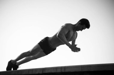 Beton yüzeyindeki tahta egzersiz yaparak atlet. Mavi gökyüzü üzerinde egzersiz sporcu. Ab kas ve fit vücut olan adam. Fitness ve spor. Sağlıklı yaşam konsepti