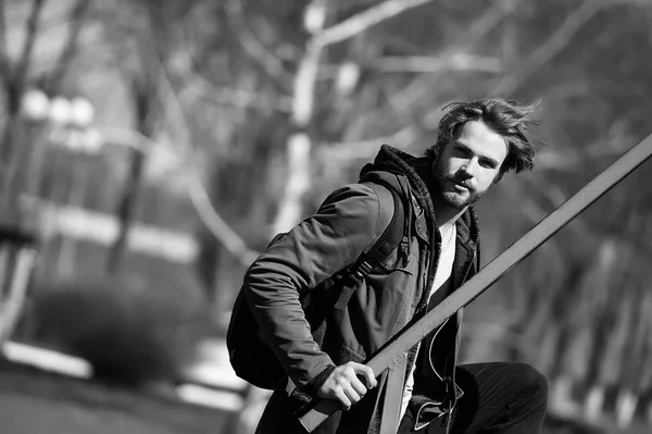 bearded man in brown hoodie jacket with sport bag