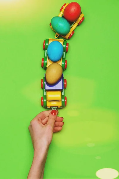 Mão feminina com ovos de páscoa coloridos em caminhão carro brinquedo — Fotografia de Stock