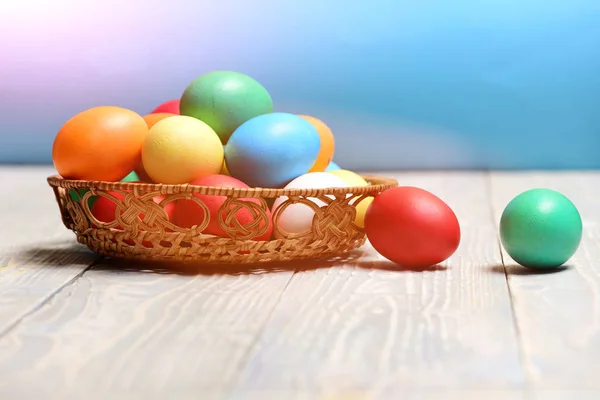 Красочные окрашенные яйца в корзину на деревянном фоне, праздник Пасхи — стоковое фото