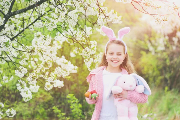 Lycklig flicka håller rosa kanin leksak och ägg — Stockfoto