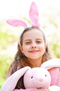 Mutlu çocuk güneşli bir günde pembe tavşan oyuncağı tutuyor.