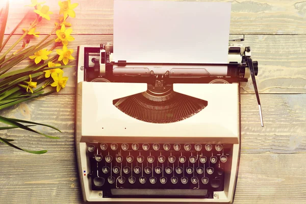 Vecchia macchina da scrivere vintage con carta e fiori di narciso in fiore primaverile — Foto Stock