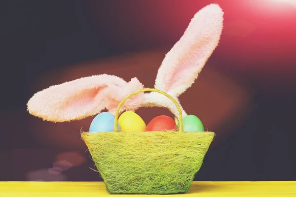 Easter basket with colored Easter eggs and furry rabbit ears