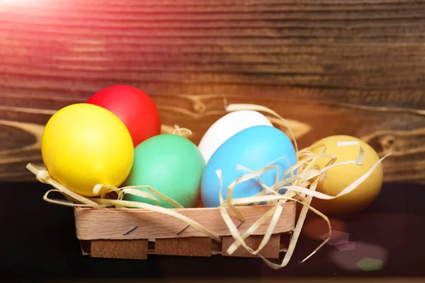 easter colorful eggs in wooden basket with straw nest