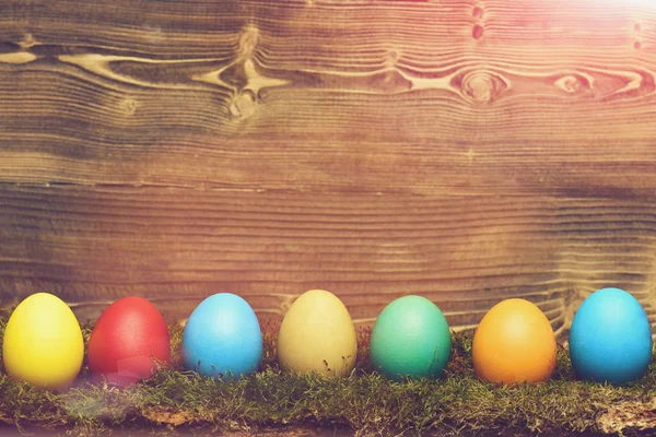Huevos coloridos de Pascua pintados con musgo verde sobre fondo de madera — Foto de Stock