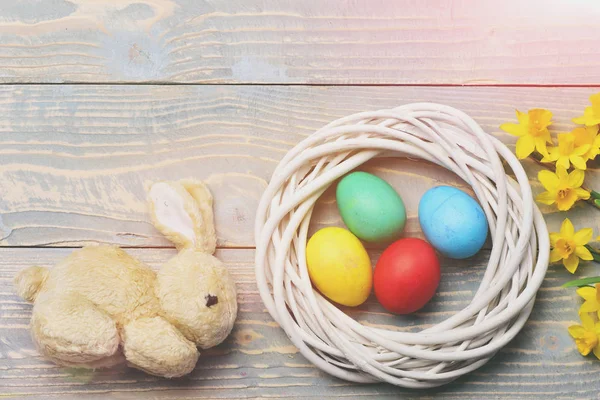 ウサギのおもちゃ黄色のナルシシズムと花輪のカラフルなイースターエッグ — ストック写真