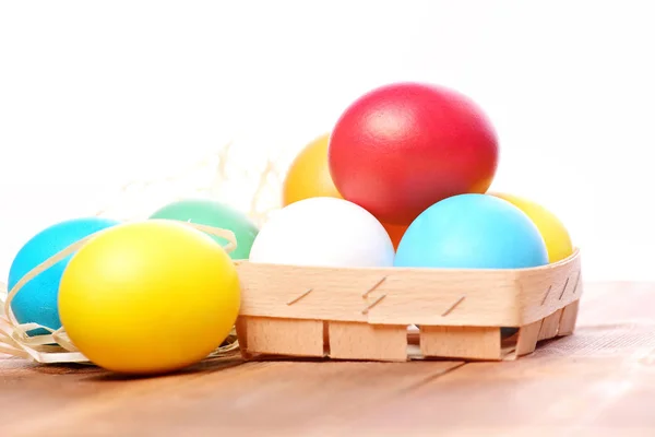 Пасхальные красочные яйца в деревянной корзине с соломенным гнездом — стоковое фото