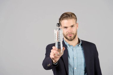 Gri arka planda plastik şişesi olan adam, susamış.