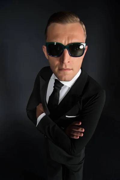 Uomo d'affari in abito nero e occhiali da sole su sfondo scuro — Foto Stock